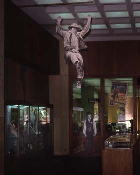 Life-sized John Wayne cut-out leaps into the center of my “Western Film” exhibit, UT Austin, 1991. Life-sized John Wayne cut-out leaps into the center of my “Western Film” exhibit, UT Austin, 1991.